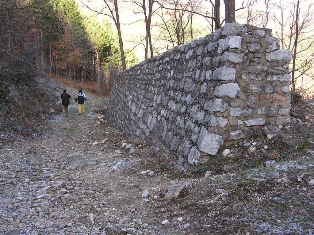 Portion of the containment wall constructed for diverting the course of the stream so that it could pass upstream of the dam. Today this stream flows once more in its original bed at the bottom of the valley. 